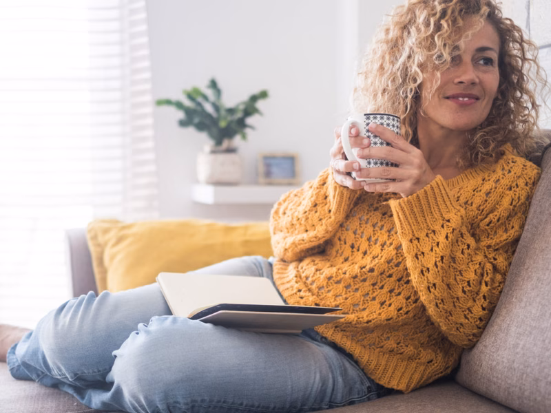 Women in sweater looking comfortable because she knows the best thermostat settings for winter