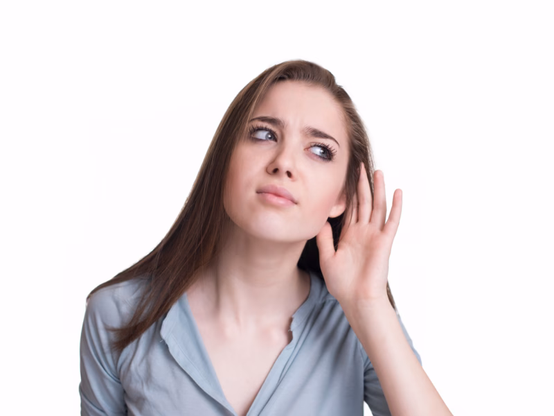 Woman looking like she hears a strange sound, making a hand to ear gesture