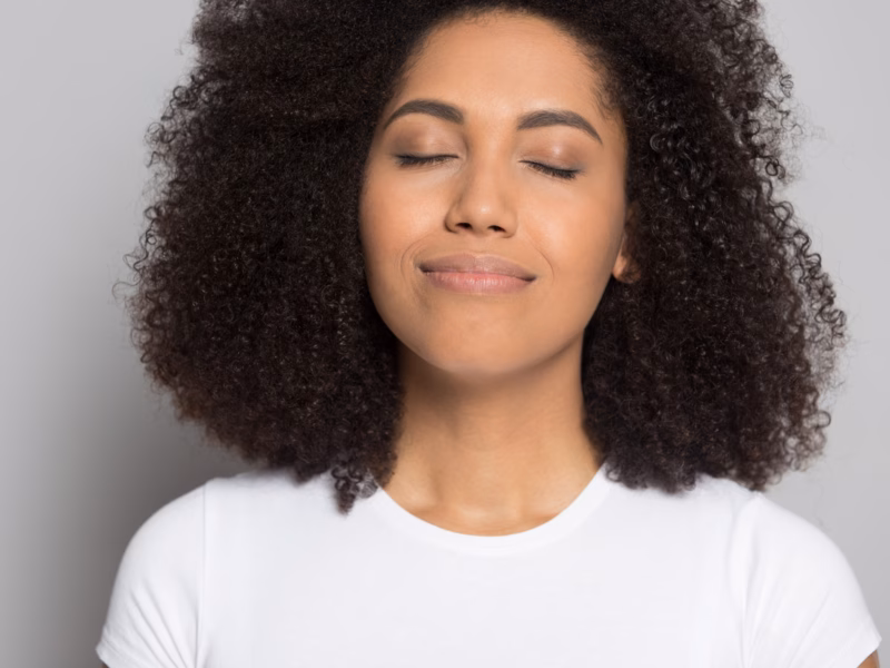 A young Black woman smells the fresh air in her home after choosing an air cleaner or air purifier