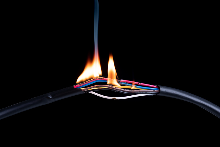 On a black background, flames emanate from exposed wires