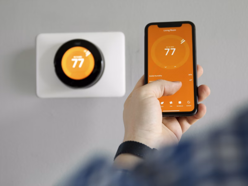 A man in Charlottesville Virginia uses their phone to program their thermostat