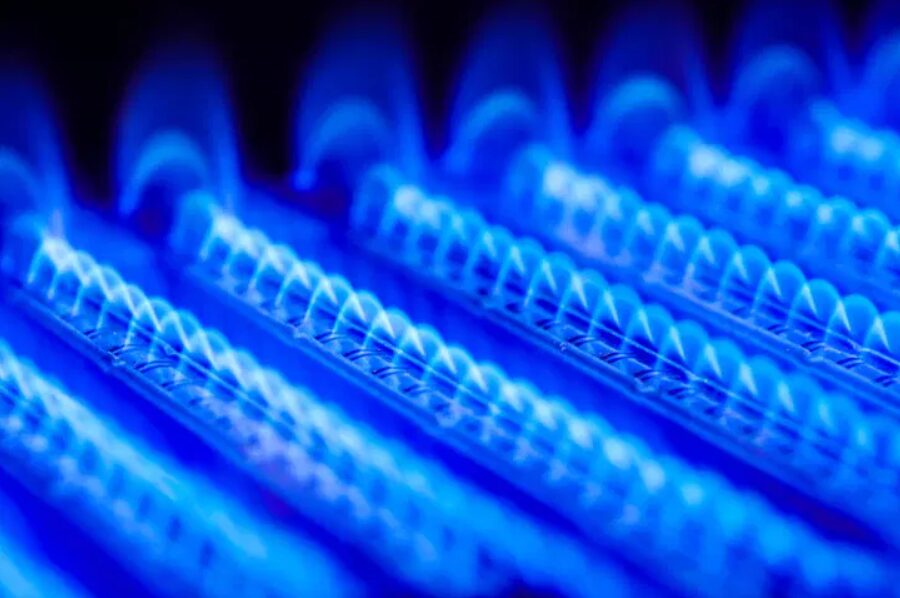 Propane flame inside of a gas boiler lights up in blue with a purple background in Charlottesville Virginia
