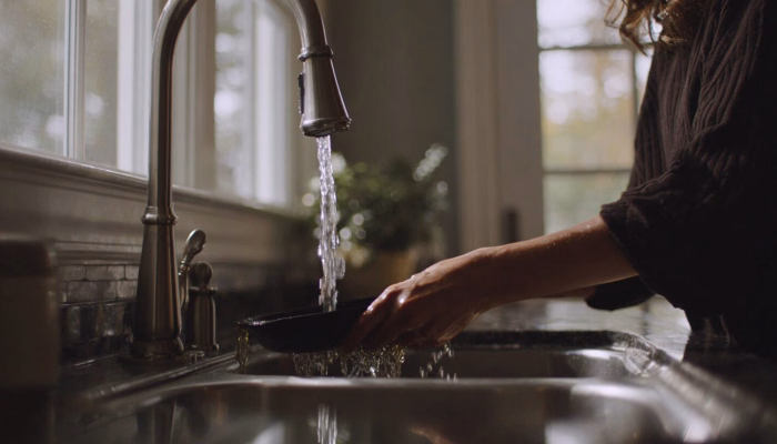 Photo of a Charlottesville-area home kitchen sink showing slow-draining water and a drain screen, illustrating early signs of grease buildup common in local households near downtown Charlottesville.